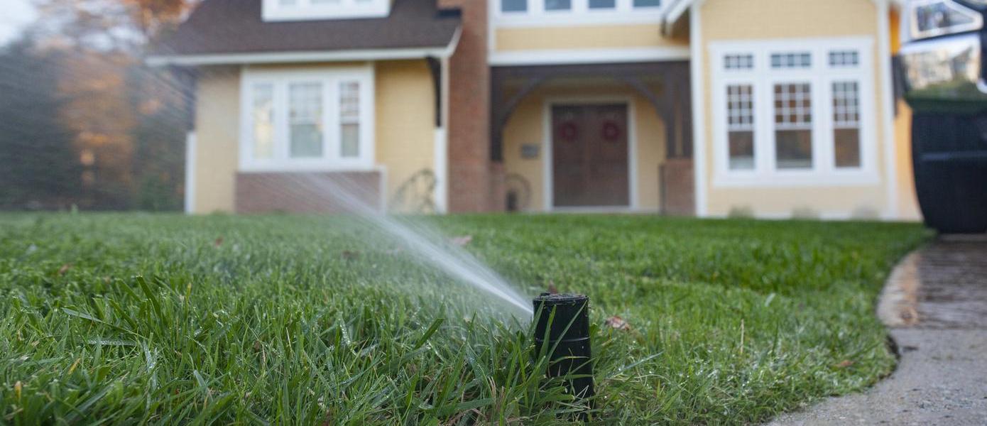 sprinklers in front of a yellow house